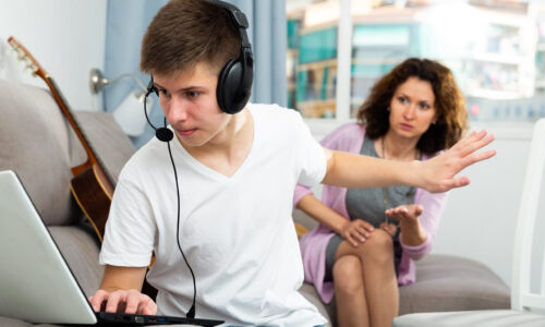 Portrait of teenager boy addicted with laptop not listening mother at home